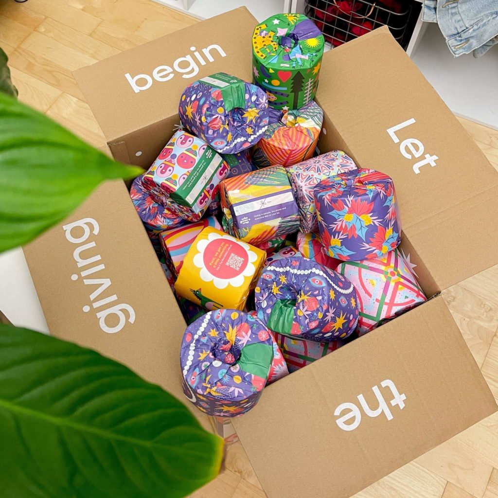 An open box of brightly colored and festive looking toilet paper brand, from the brand Who Gives A Crap