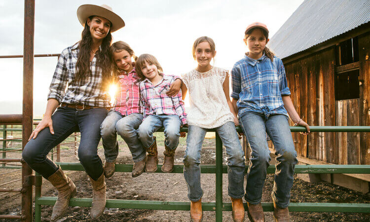 A woman and her four daughters sitting on a farmer's fence, these are Mary the owner of Five Marys Farms and her four children named Mary)